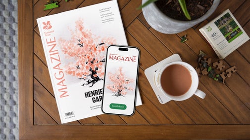 A copy of the National Trust spring 2025 Magazine on a table and a phone showing the digital edition